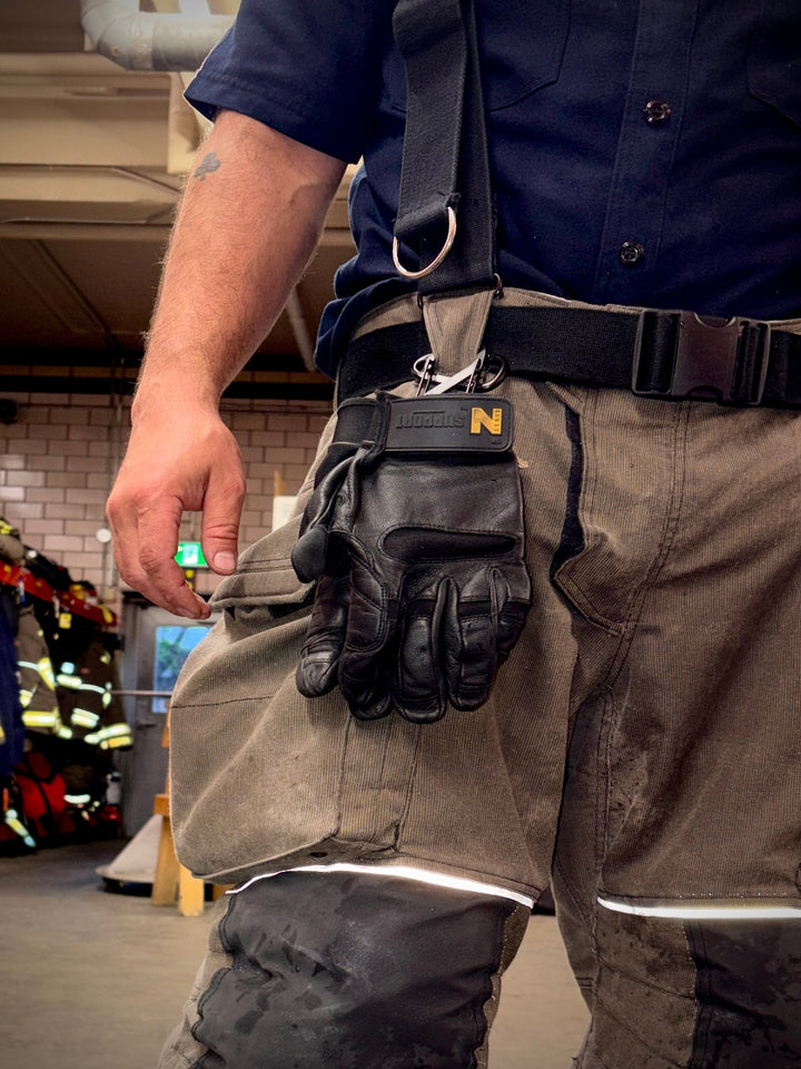 firefighter hangs leather gloves from his pants
